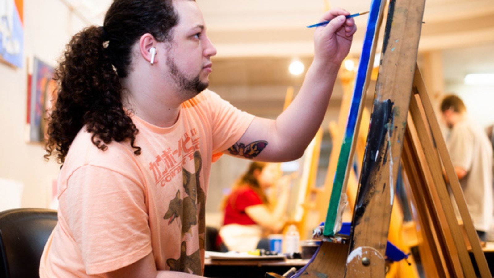 a man with long hair drawing on a board
